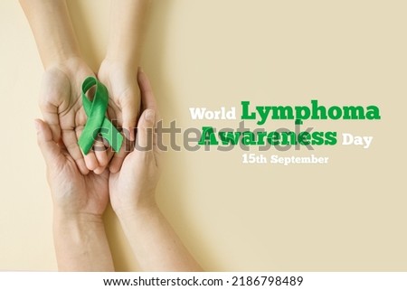 Hands of mother and child hold green ribbon - symbol of fight against disease. World lymphoma awareness day. September 15. Liver, Gallbladders bile duct, kidney Cancer and Lymphoma Awareness month Royalty-Free Stock Photo #2186798489