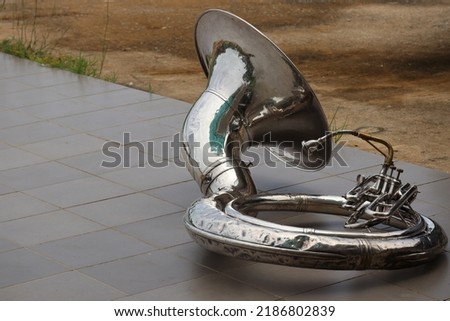 Sousaphone is the largest brass instrument in the marching band. Put on a cement background