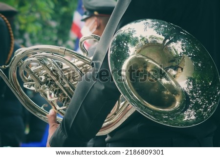 back view of a man in military uniform holding a French horn instrument