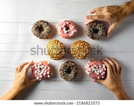Unrecognizable people pick up Donut from a wooden table. Top View Flat Laying