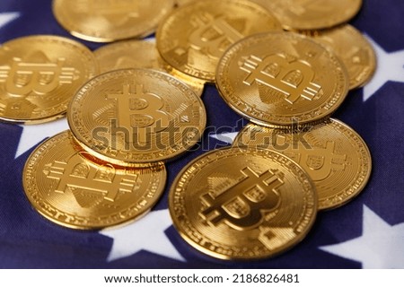 The concept of the economic crisis. Bitcoin gold coins lie on the American flag. Beautiful photo images of gold Bitcoin coins. Cryptocurrency with images of the American flag. Coins close-up. Top view