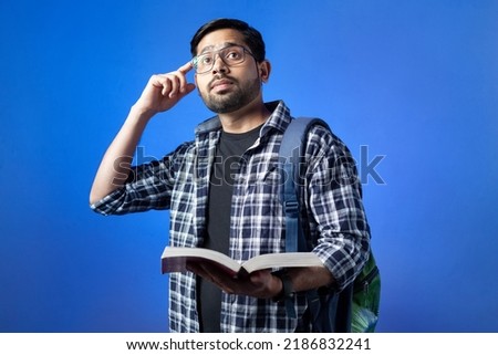 Adult male student studying and thinking about his career, isolated on blue background.