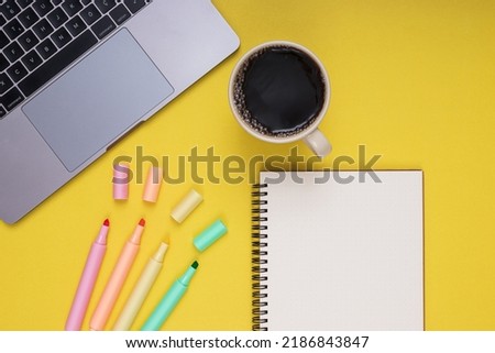 Laptop, notepad, colored pencils, coffee mug. back to school. Isolated yellow background