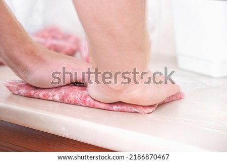 A man makes flat minced pork and beef in bags for storage in the freezer.