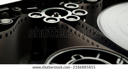 a roll of film in a film camera cassette. negative film in the tape drive mechanism of the cassette. show business film production technology concept