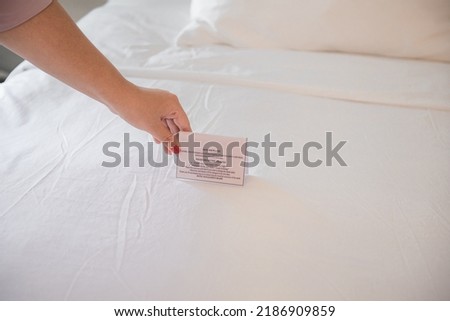 Woman hands putting a card on the bed, she wants to change bed sheets 