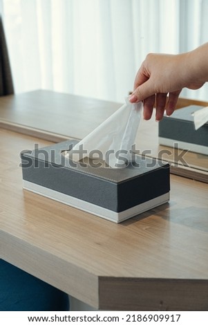 Woman hand picking up tissue paper from tissue box on makeup table. Royalty-Free Stock Photo #2186909917