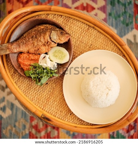 Indonesian Food Deep Fried Fish, Cucumber, Basil Leaves, Cabbage and Chili Paste Served on the Clay Pot with Warm Rice Royalty-Free Stock Photo #2186916205