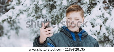 A young man in winter clothes takes a selfie in a winter snowy forest. Happy guy with a hike in the street Concept of recreation, sport and people. photo banner