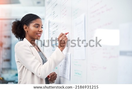Project manager writing on a whiteboard to plan ideas and visualize business strategy. Focused, confident and thoughtful businesswoman showing ambition and dedication while working in an office