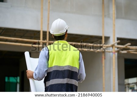 Foreman wear helmet and use blueprint for check house plan on construction village site