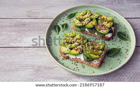 Toast with avocado, cottage cheese, spinach, sesame seeds, flax seeds. Healthy food rich in fiber, trace elements, omega acids, unsaturated lipids. Royalty-Free Stock Photo #2186957187