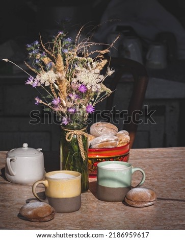 Homemade rustic tea party for two persons in a harsh light, simple table setting with a bouquet of wildflowers and muffins