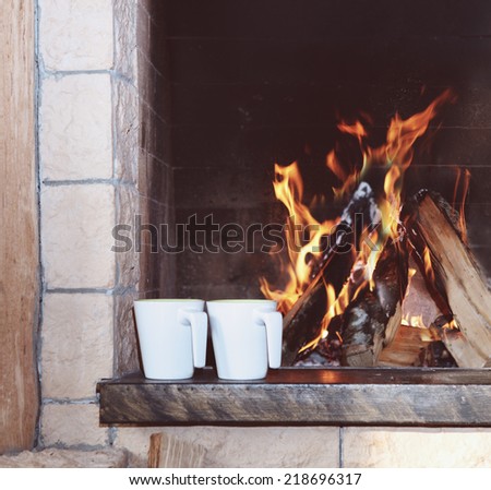 Two mugs near the fireplace with fire