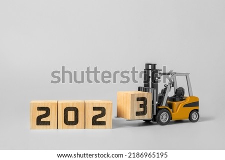 2023 happy new year background. new year industrial concept, forklift carrying box to complete 2023 text isolated on grey background.