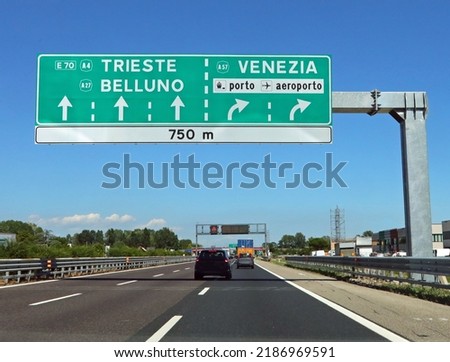 Motorway junction with large sign with directions to major cities in Italian such as Venice and the airport
