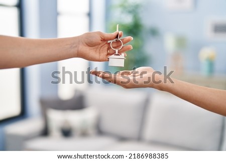 Young woman holding key of new house at home Royalty-Free Stock Photo #2186988385