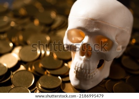 Skull replica and gold coins on black background.