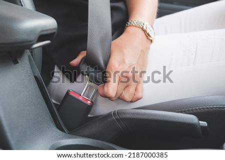 Close-up of a woman's hand fastening a seat belt in a car. Woman driver fastens her seat belt before driving. Driving safety concept. Royalty-Free Stock Photo #2187000385