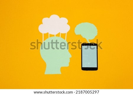uman paper head uploads information to the cloud, mobile phone uploads information to the human brain, creative art design, on a yellow background, abstract idea