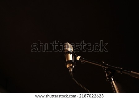 Studio condenser microphone on boom microphone stand on black background in low angle view