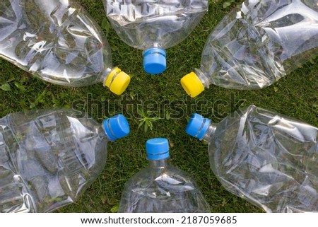 Six plastic empty bottles for recycling and preserving the planet. Bottles with colorful lids on a background of green grass