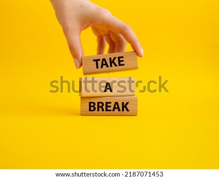 Take a break symbol. Concept words 'Take a break' on wooden blocks. Beautiful yellow background. Businessman hand. Business and Take a break concept. Copy space.