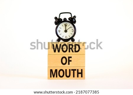 Word of mouth symbol. Concept words Word of mouth on wooden blocks on a beautiful white table white background. Black alarm clock. Business, finacial and word of mouth concept. Copy space.