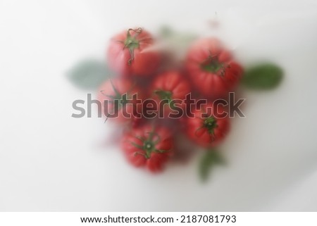 Abstract blur filter photo, group of beautiful fresh red tomatoes with green basil leaves and berries on a light background