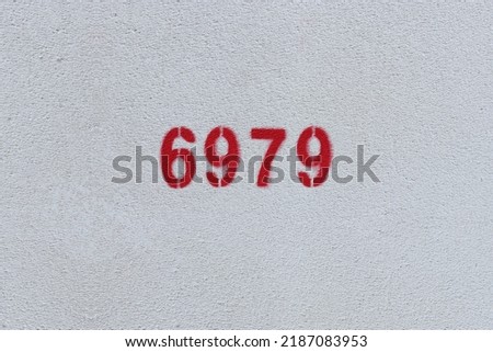 Red Number 6979 on the white wall. Spray paint.
