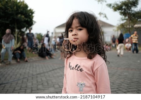 Indonesian cute little girl is in a competition to insert rubber bands into straws