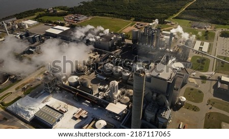 A dynamic aerial footage tilting downward towards the UPM Fray Bentos pulp mill factory located on the banks of the River Uruguay. The mill produces bleached hardwood eucalyptus pulp. Royalty-Free Stock Photo #2187117065