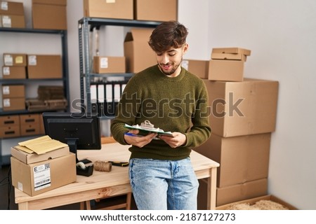 Young arab man ecommerce business worker writing on checklist at office