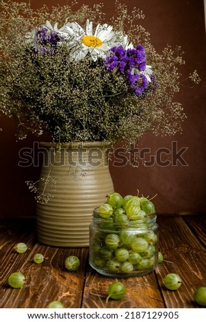 Gooseberries and flowers on the wooden table. Flowers and berries on a wooden table. 