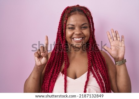 African american woman with braided hair standing over pink background showing and pointing up with fingers number six while smiling confident and happy. 