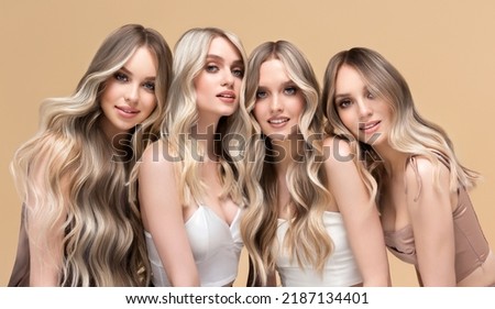 Four beautiful women    with hair coloring in ultra blond. Stylish hairstyle curls done in a beauty salon. Fashion girls , cosmetics and makeup. Royalty-Free Stock Photo #2187134401