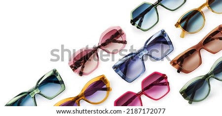 Sunglasses composition in many bright colors in transparent plastic. Top view with shadow. Trendy glasses isolated on white background. Glasses with polarized lenses. Fashionable eyewear for women. Royalty-Free Stock Photo #2187172077