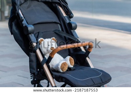 Soft toy teddy bear sitting in a baby stroller on blurred background of city street Royalty-Free Stock Photo #2187187553
