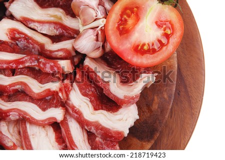 raw beef asado ribs with thyme and tomatoes on wooden board isolated over white background
