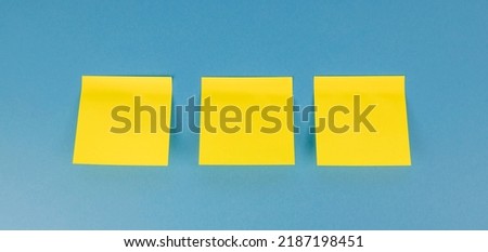 Three yellow blank square stickers on a blue background with copy space. Reminder and combination concept - close-up Royalty-Free Stock Photo #2187198451