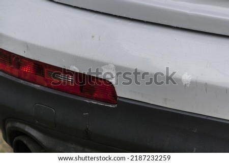 Scratched rear bumper on a white car, cracks and bumper repair close-up. White car with a broken and cracked bumper Royalty-Free Stock Photo #2187232259