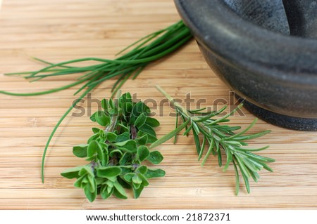 Freshly picked oregano, rosemary, and chives on a wooden kitchen desk