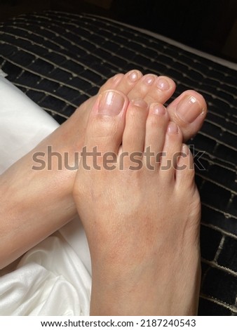 Closeup photo of woman bare feet with natural toenails lying on bed