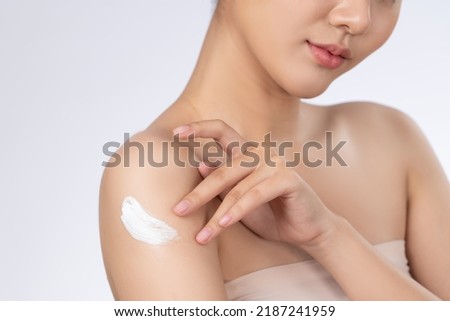 Close up gorgeous girl with soft makeup applying moisturizing skincare cream on shoulder isolated over white background. Skincare cream applied by female model concept. Healthy clean fresh skin. Royalty-Free Stock Photo #2187241959
