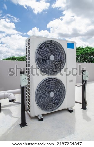 Air conditioning (HVAC) on the roof of an industrial building with blue sky and clouds.