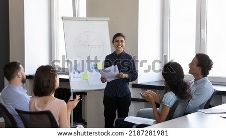 Indian businesslady trainer finish presentation on flip chart for corporate staff, accomplish training, employees applauding express gratitude for received information. Seminar, recognition concept