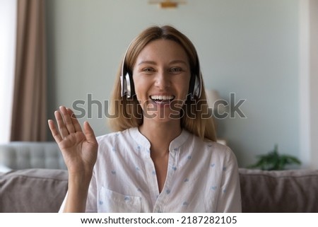 Pretty woman wear headphones greeting friend start video conference sit on sofa at home looks happy, glad to see family, enjoy distance communication use video call app, head shot. Modern tech Royalty-Free Stock Photo #2187282105
