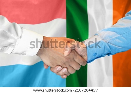 Business handshake on background of two flags. Men handshake on background of Luxembourg and Ireland flag. Support concept
