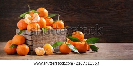 Fresh mandarin oranges fruit or tangerines with leaves in a box on wooden background Royalty-Free Stock Photo #2187311563