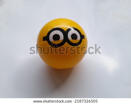 Children toy yellow plastic ball with minion character top view on a white background. game background concept, games, playing, hobbies, hobbies, lifestyle, educational toys, action figure, gift